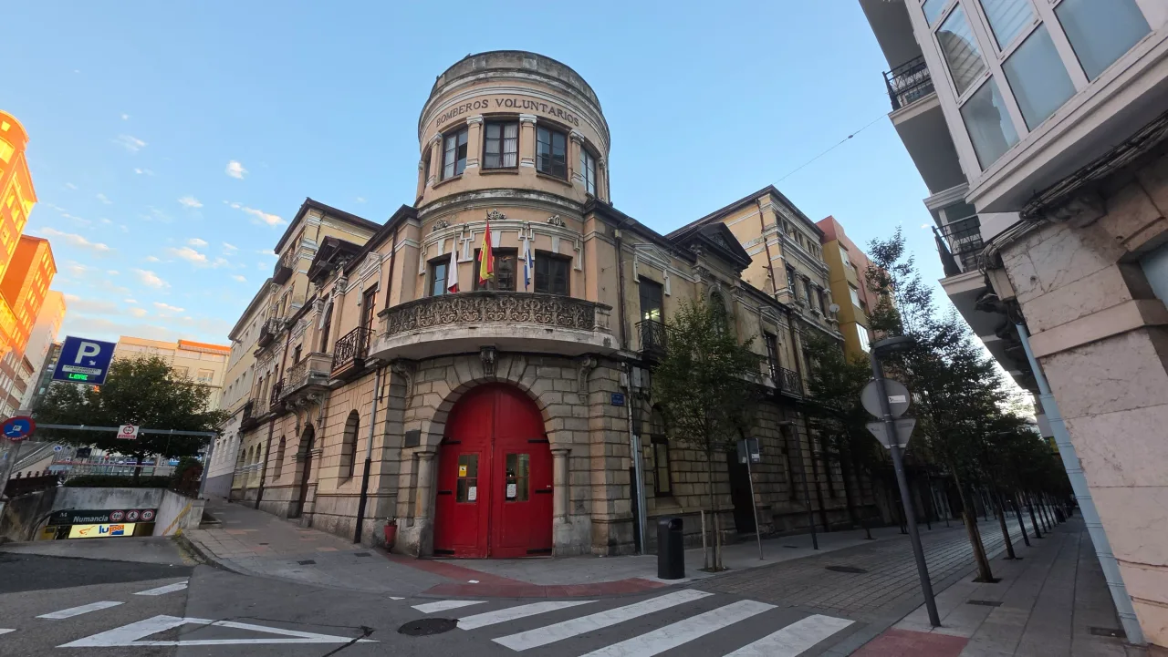 Parque de Bomberos Voluntarios en Numancia, con torre circular, balcón curvo y puertas rojas bajo arcos de piedra