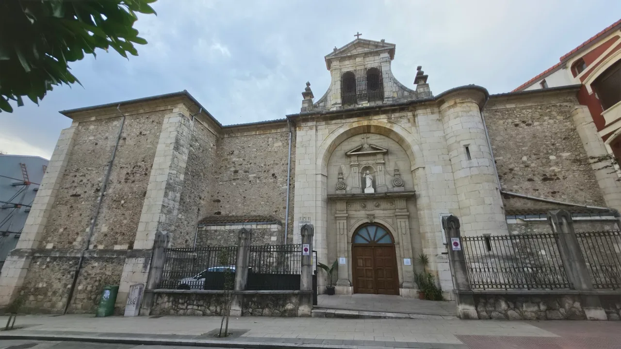 Vista oblicua de la iglesia de Consolación desde la Calle Alta, con su portada de piedra, espadaña y muro lateral