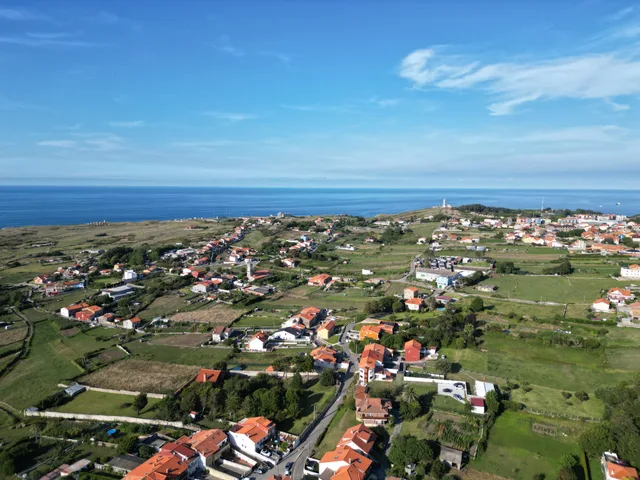 Vista aérea de Cueto en 2023 con el faro de Cabo Mayor al fondo