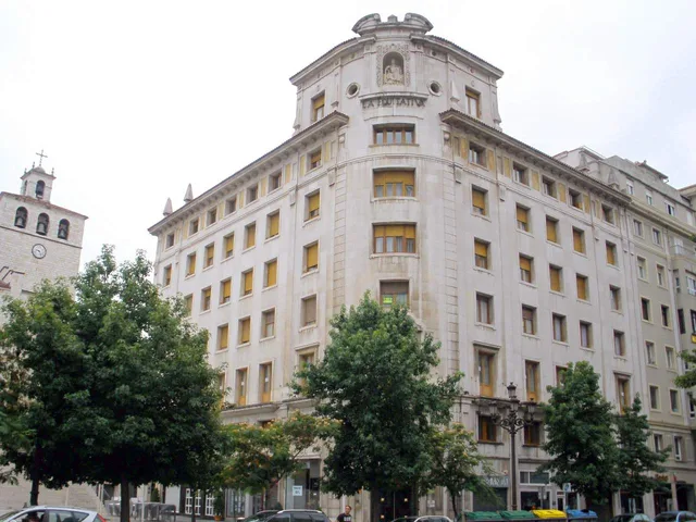Vista completa del edificio de La Polar, de piedra clara y con torreón en la esquina, junto al entorno de la catedral de Santander