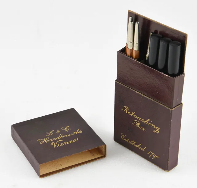 Caja marrón abierta con lápices y útiles de retoque fotográfico fabricada hacia 1930