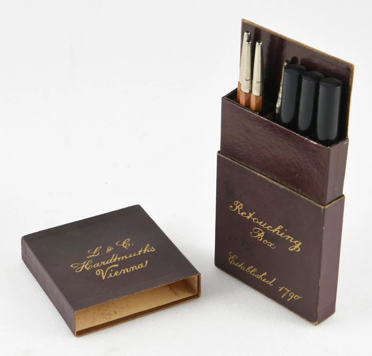 Caja marrón abierta con lápices y útiles de retoque fotográfico fabricada hacia 1930