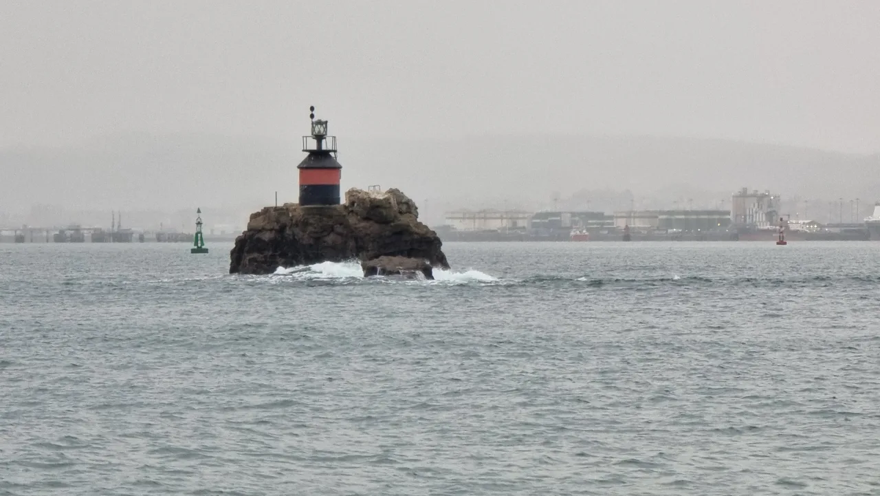 Baliza roja y negra con dos esferas sobre la Peña Horadada y boyas al fondo