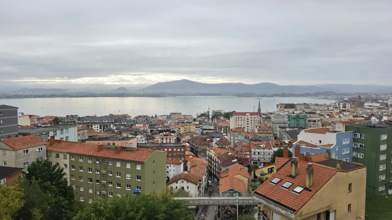 Vista desde lo alto del funicular del Río de la Pila, con una pasarela en primer plano, viviendas escalonadas, tejados del centro y la bahía al fondo