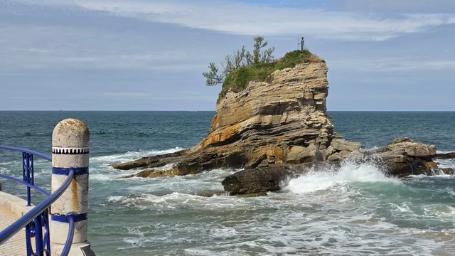 Farallón estratificado de la ensenada de El Camello coronado por la escultura Neptuno Niño